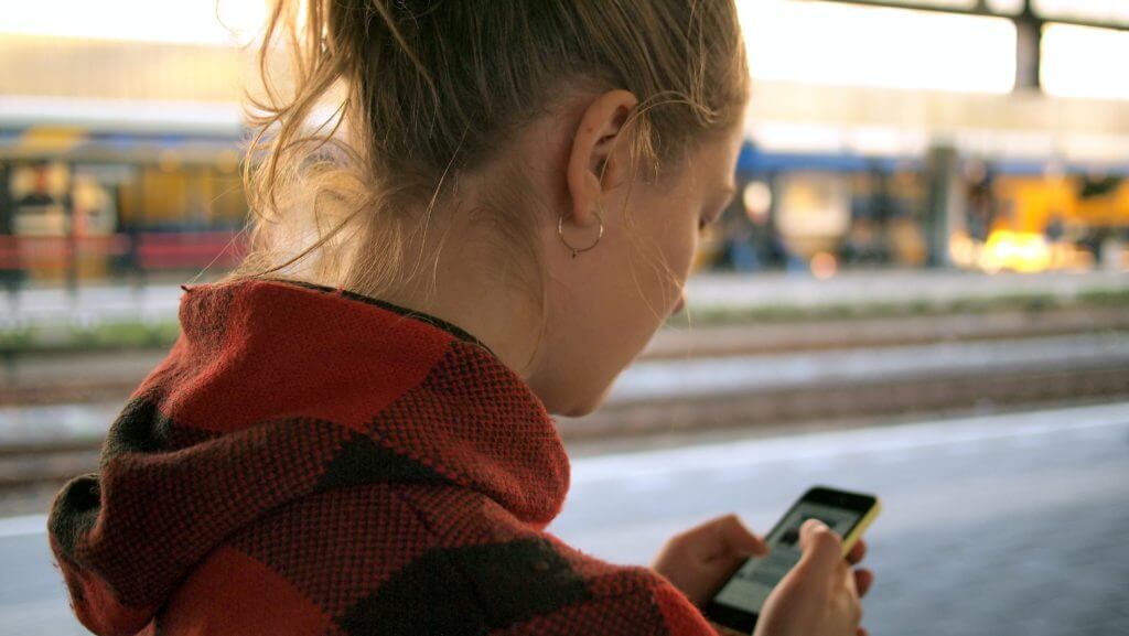 Une femme consulte son téléphone portable avec attention, absorbée par l'écran.