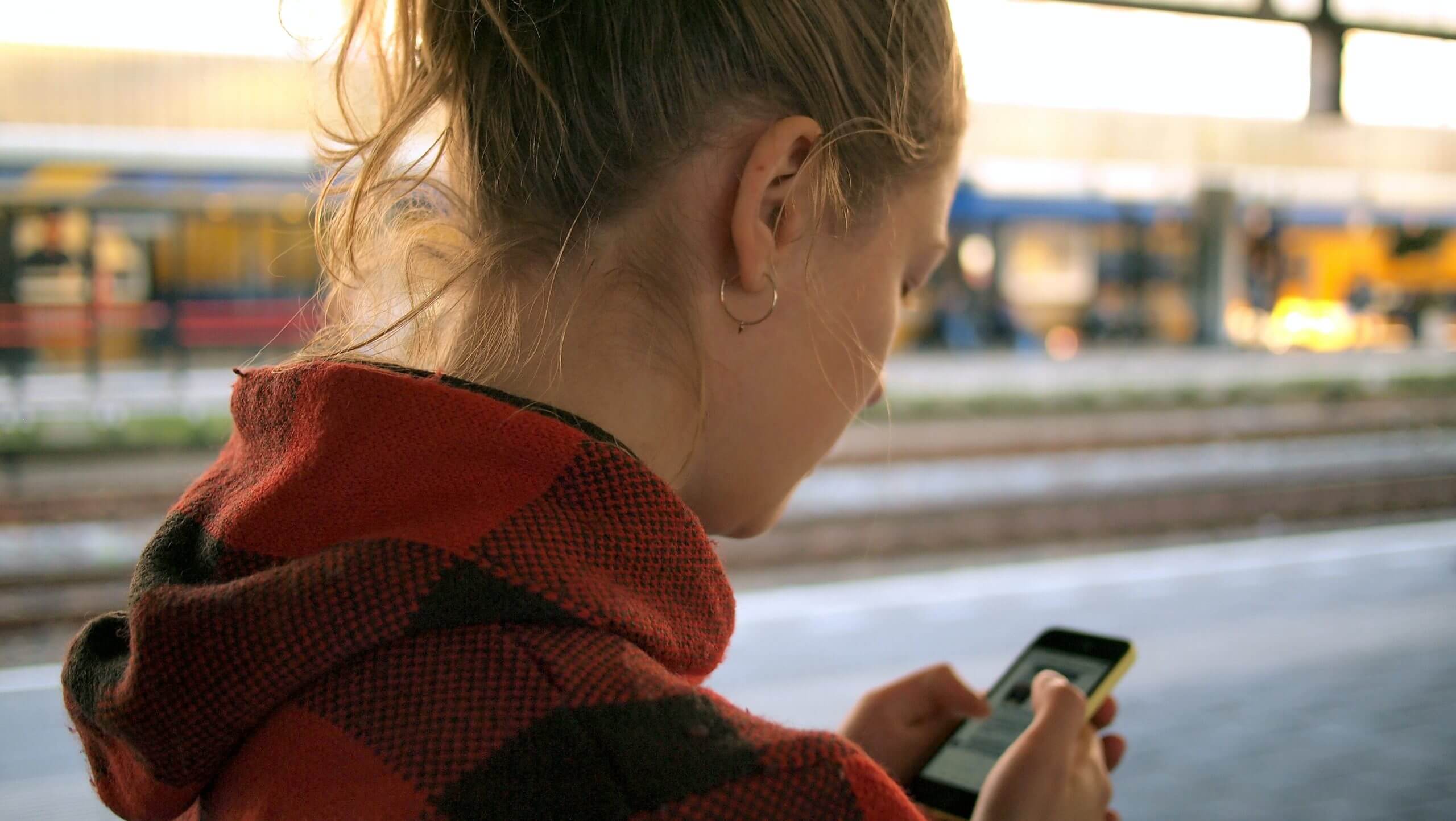 Une femme consulte son téléphone portable avec attention, absorbée par l'écran.
